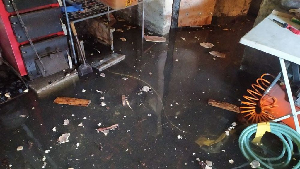 Zalane posesje, powalone drzewa, wyrwa w drodze