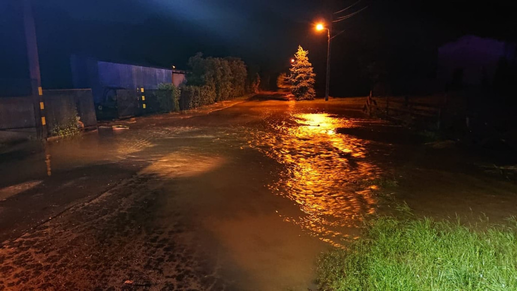 Zalane posesje, powalone drzewa, wyrwa w drodze