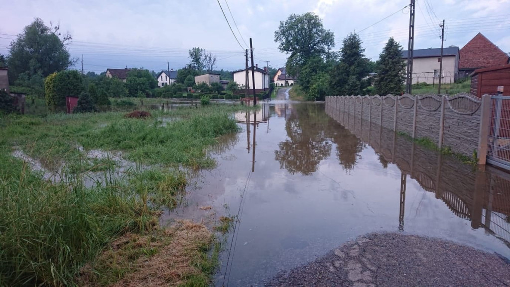 Zalane posesje, powalone drzewa, wyrwa w drodze