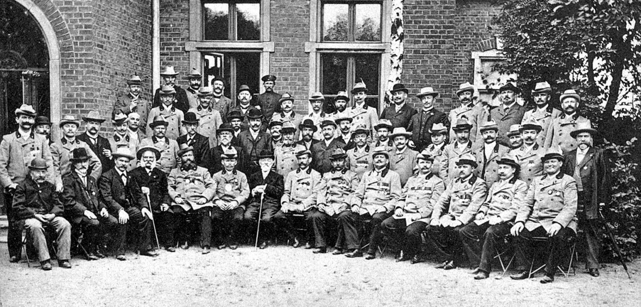 Członkowie tarnogórskiego bractwa przed budynkiem strzelnicy. Pocztówka pamiątkowa z zawodów w Zielone Świątki 1905 r. Źródło: Historia Tarnowskich Gór, red. J. Drabina, Tarnowskie Góry 2000. 