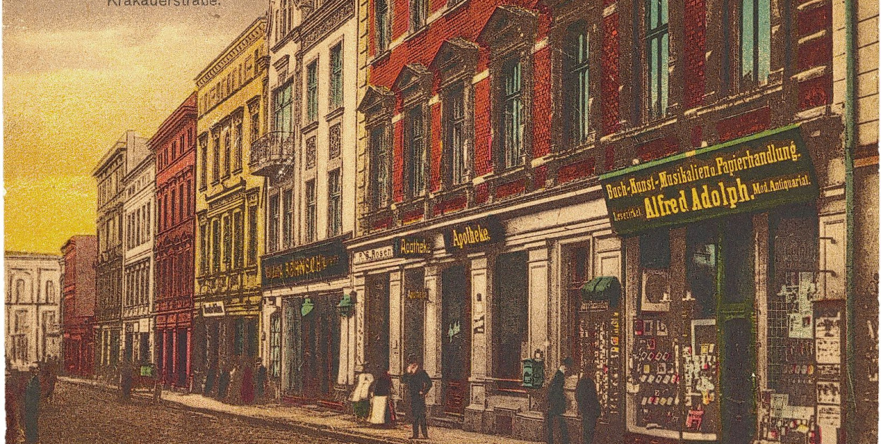 Fragment ul. Krakowskiej. Na pierwszym planie witryna księgarni Alfreda Adolpha, pocztówka pochodząca z lat 1907–1914; wł. Beata i Jacek Kalke
