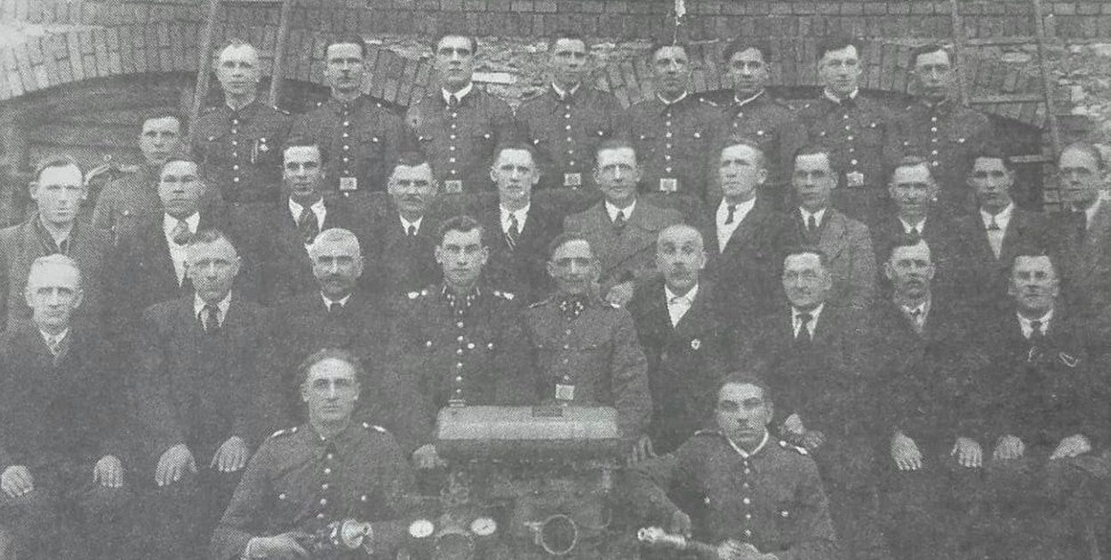 Druhowie z OSP Ożarowice na tle starej remizy. Lata 50. XX w. Fot. Archiwum