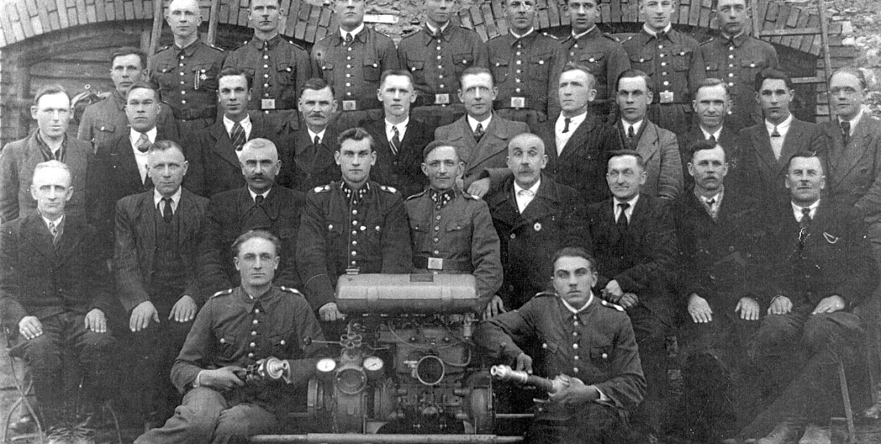 Druhowie OSP Ożarowice na tle starej remizy. Zdjęcie z lat 50. ubiegłego wieku